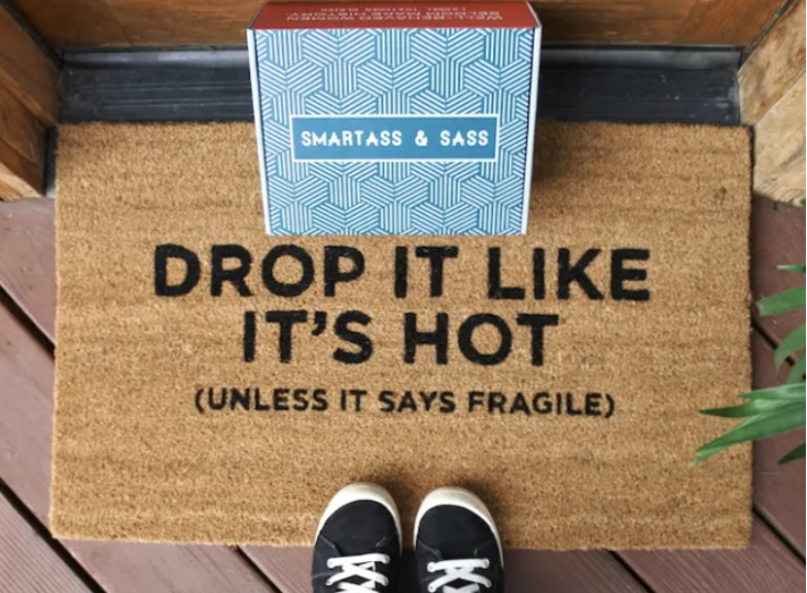 smartass and sass box on a doorstep mat that says drop it like it's hot unless it says fragile