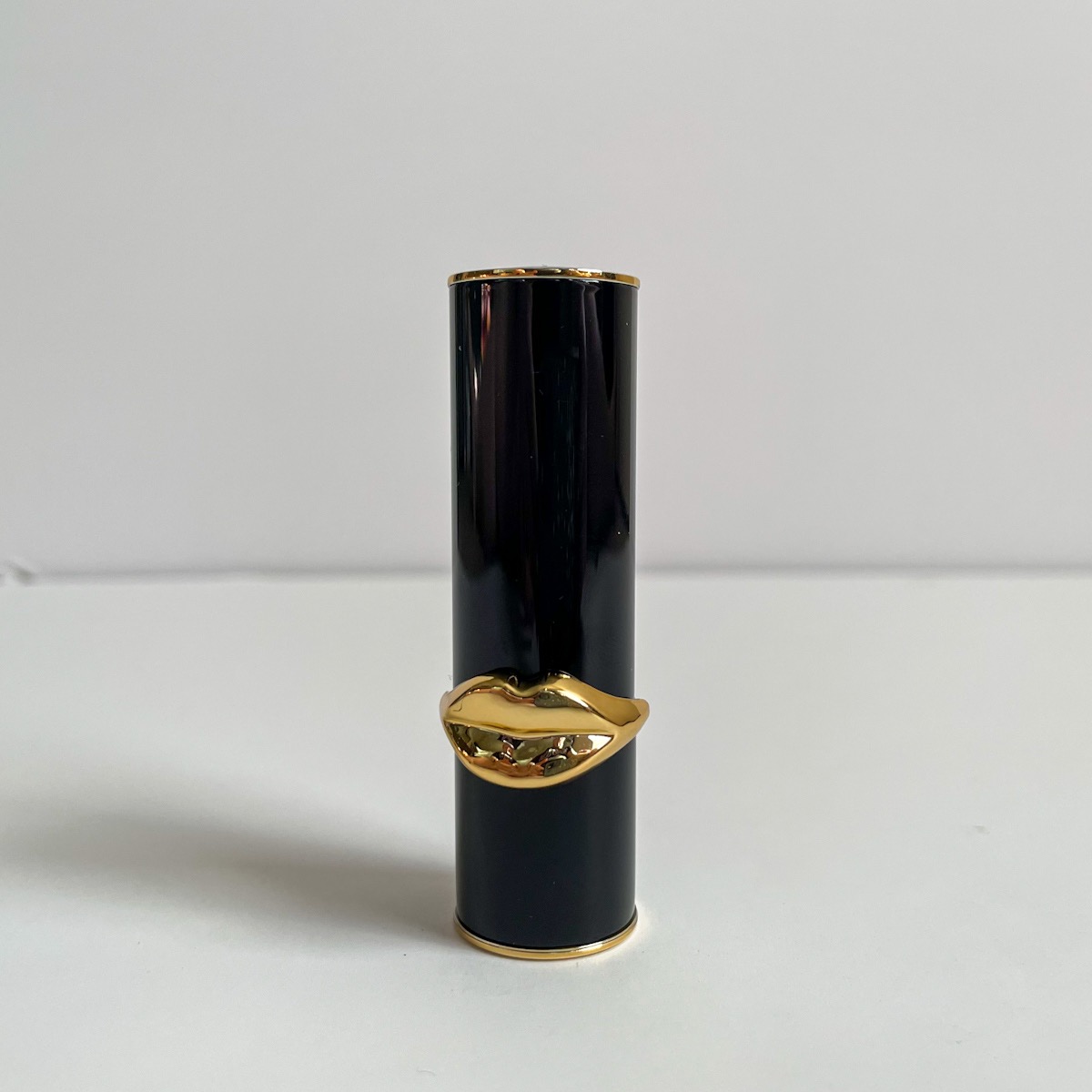 closed black tube of lipstick with gold lips