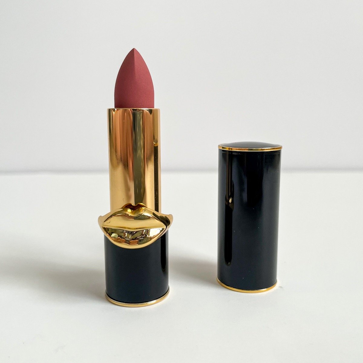 opened black tube of lipstick showing pink-brown shade