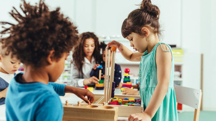 Adorable little children and their teacher playing with toys at kindergarten