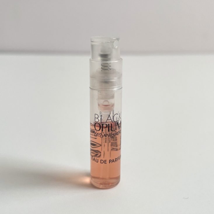 clear perfume vial with black lettering and white nozzle showing pink perfume