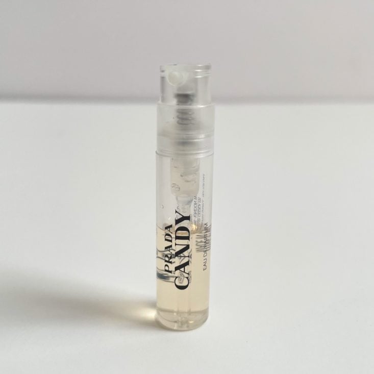 clear perfume vial with black lettering and white nozzle showing yellow perfume