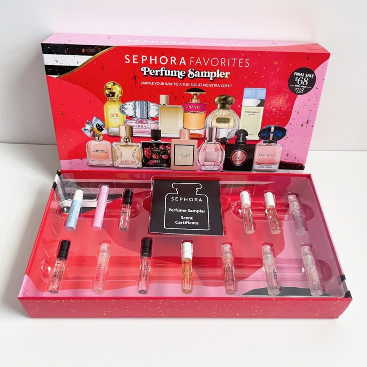 open box showing the perfume samples nestled in plastic with black voucher and the top of the box displayed behind it