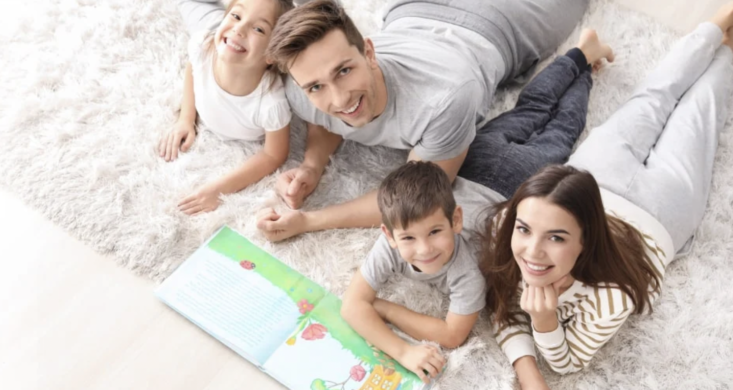 parents and children lying on a rug reading