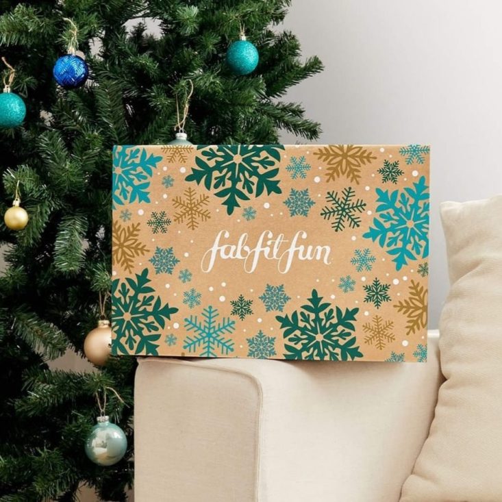 photo of FabFitFun Winter Box on white couch with Christmas tree in background