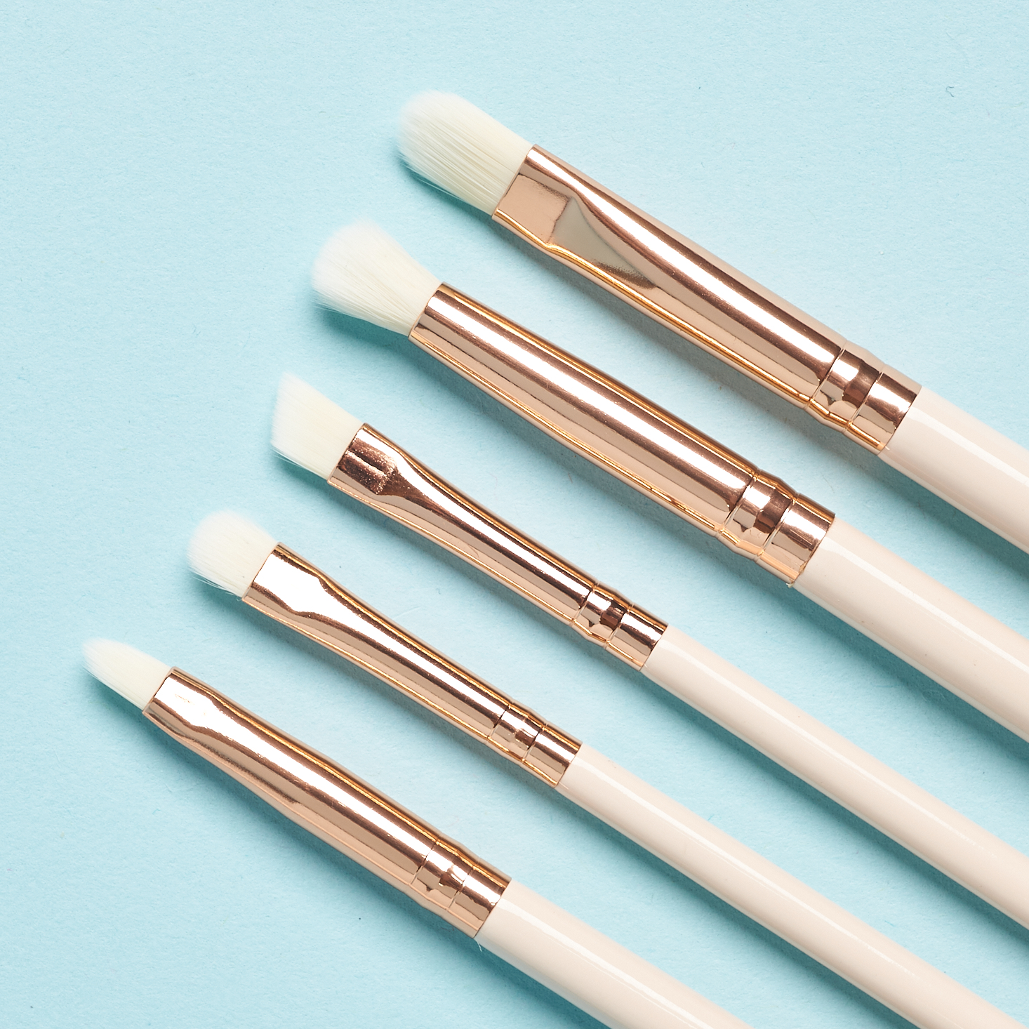 closeup of white brushes with white brush heads and metallic gold attachments.