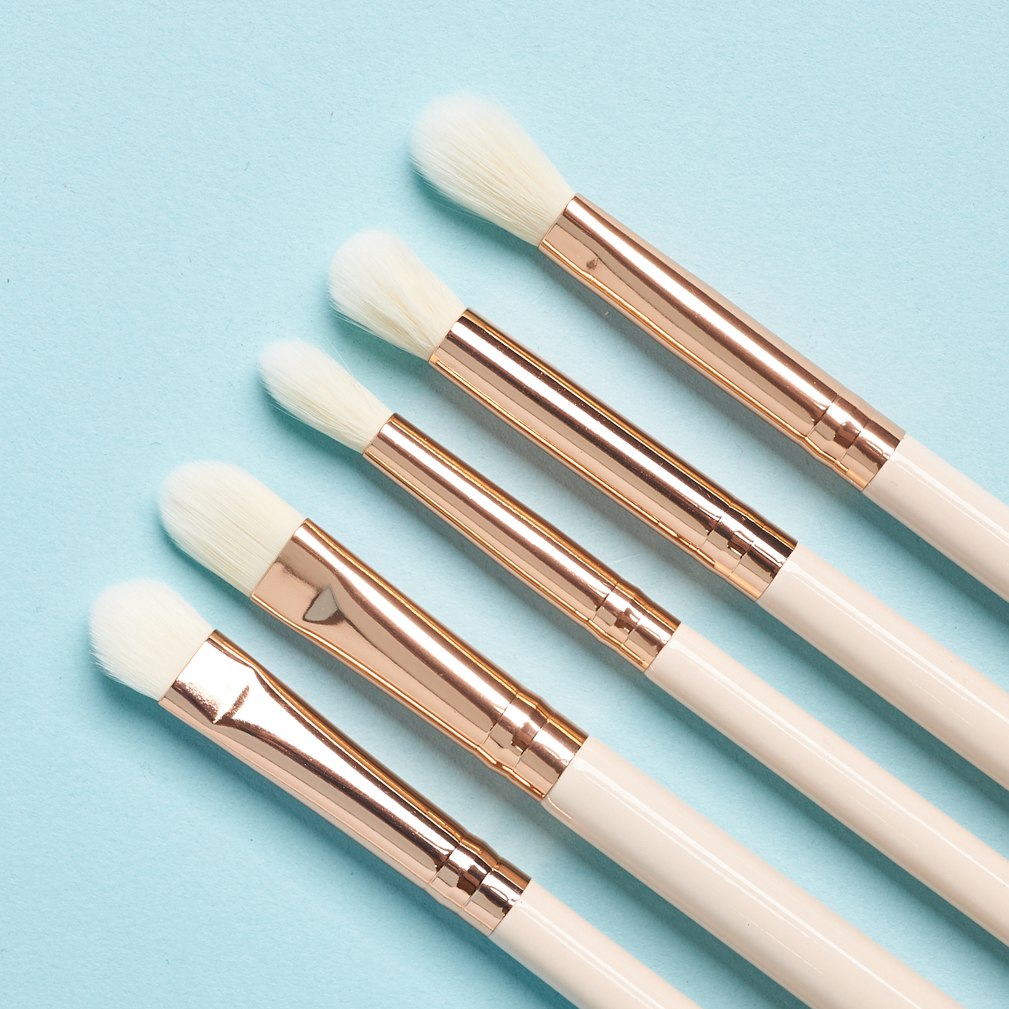 closeup of white brushes with white brush heads and metallic gold attachments.