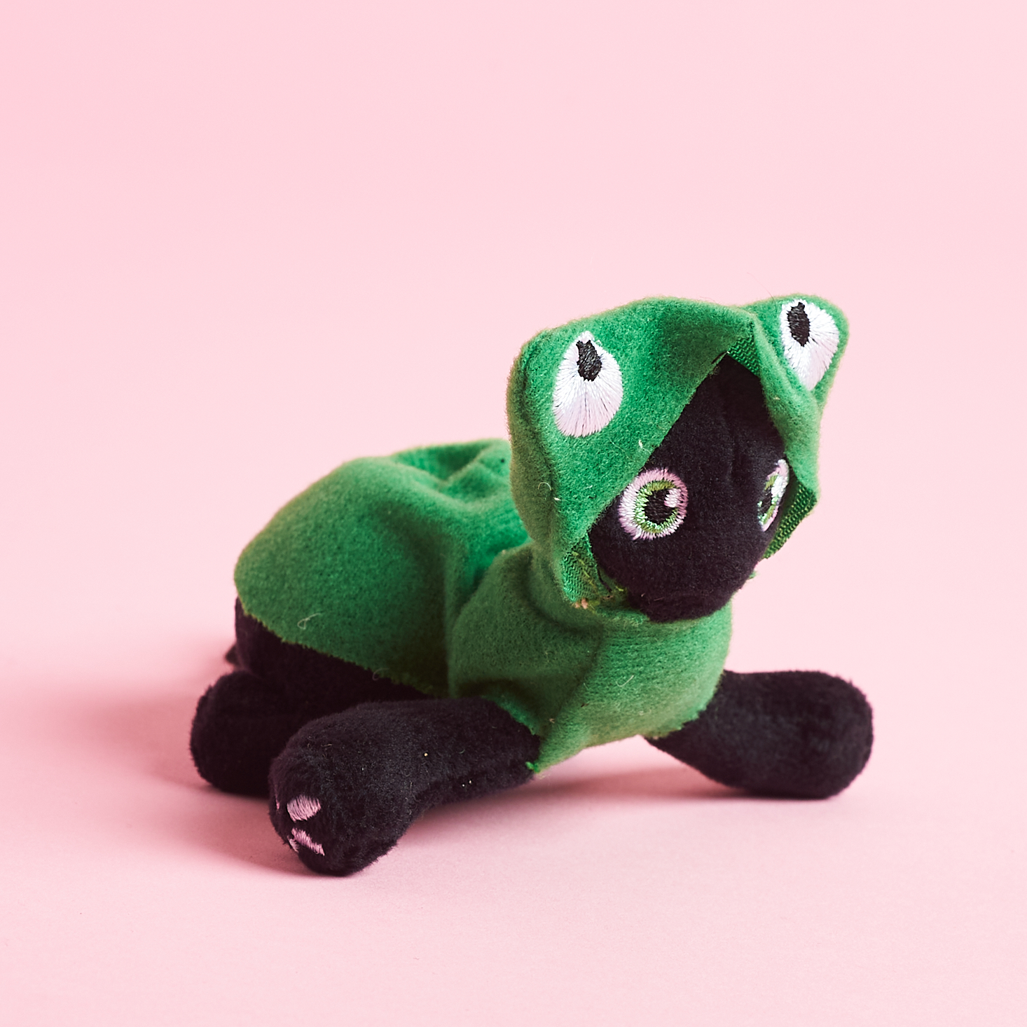 black cat toy wearing frog costume