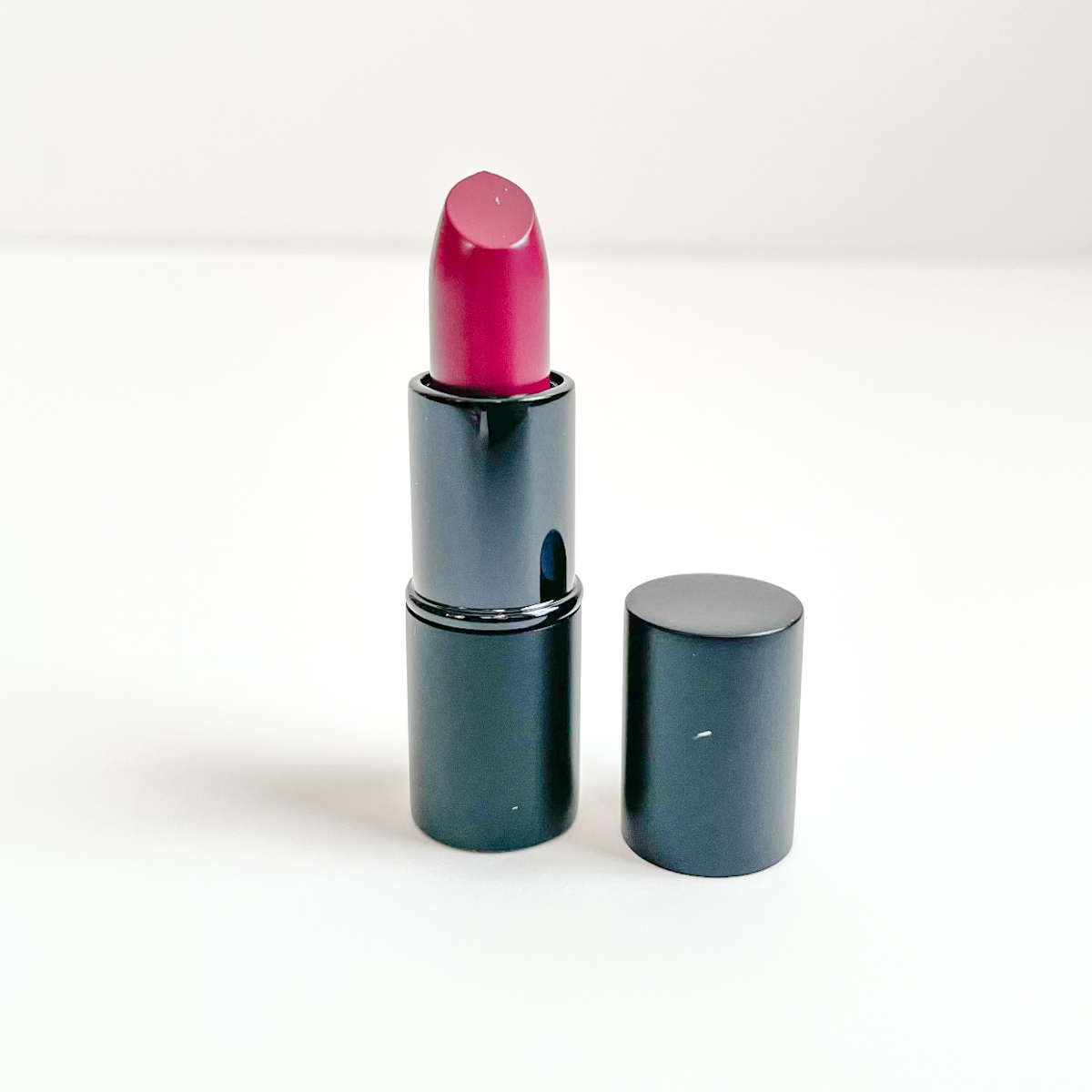 black tube of lipstick opened to show deep berry