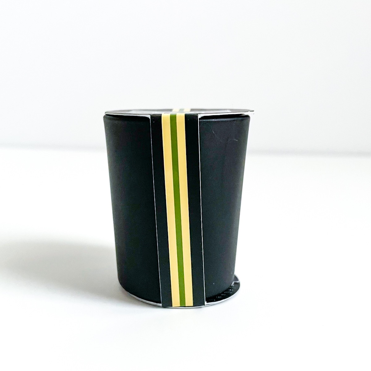 black candle vessel with yellow and black paper packaging