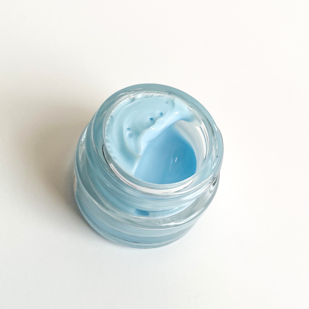 opened glass jar showing blue cream