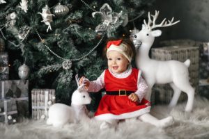 baby girl in front of Christmas tree in Christmas clothes 