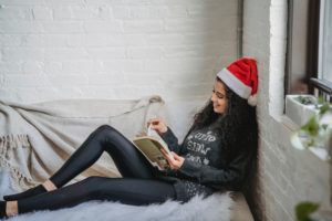 women reading book wearing christmas hat in room 