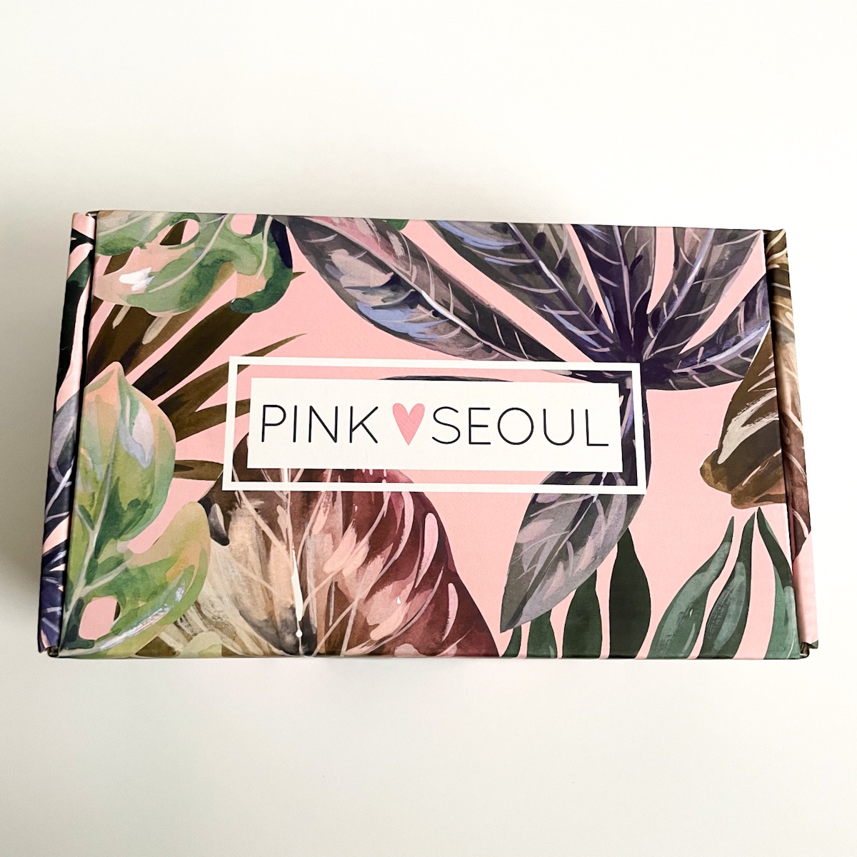 pink box with palm tree leaves