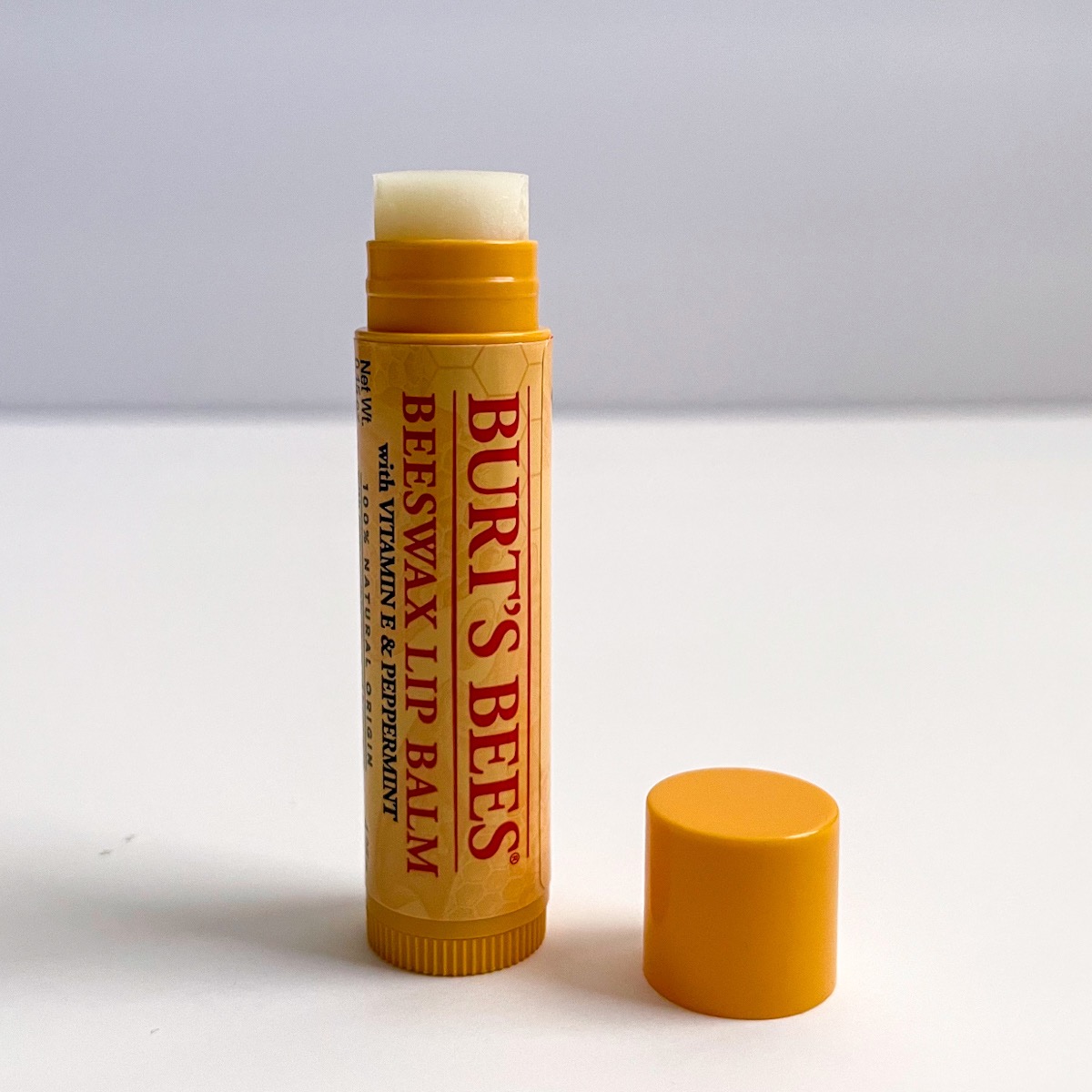 yellow and red tube of lip balm, opened showing white balm texture