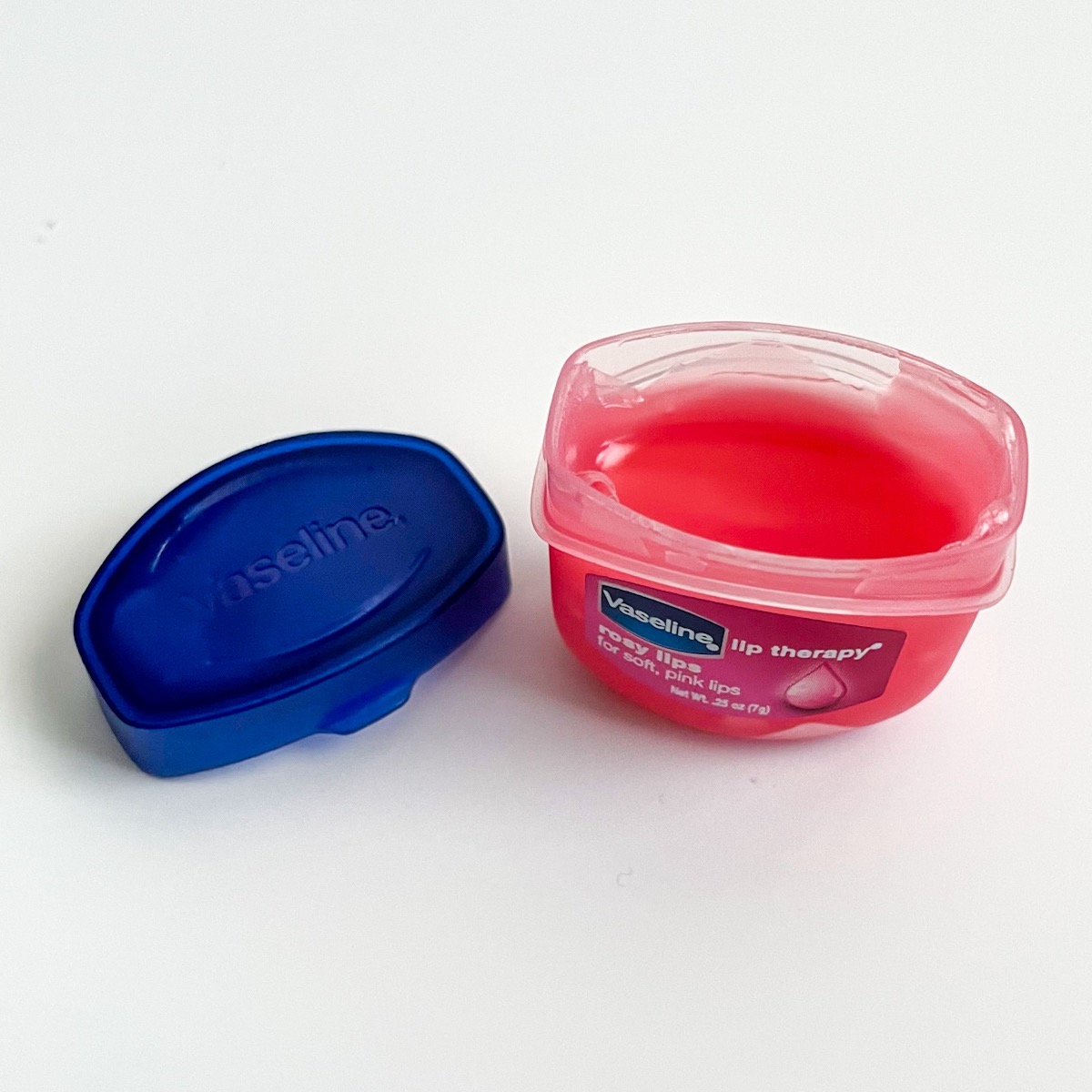 opened pink tub of vaseline with blue lid next to it