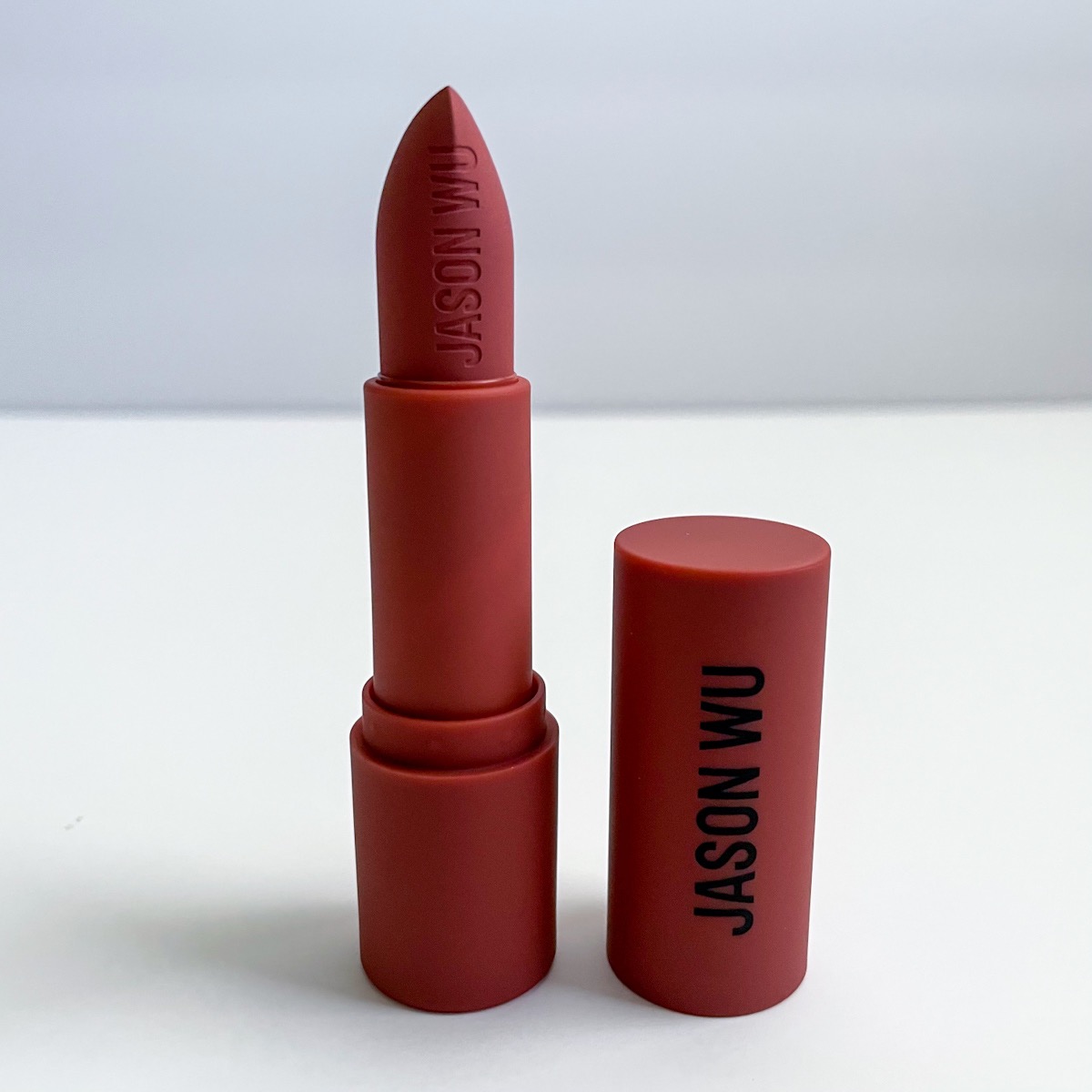 opened rust lipstick with lid next to it