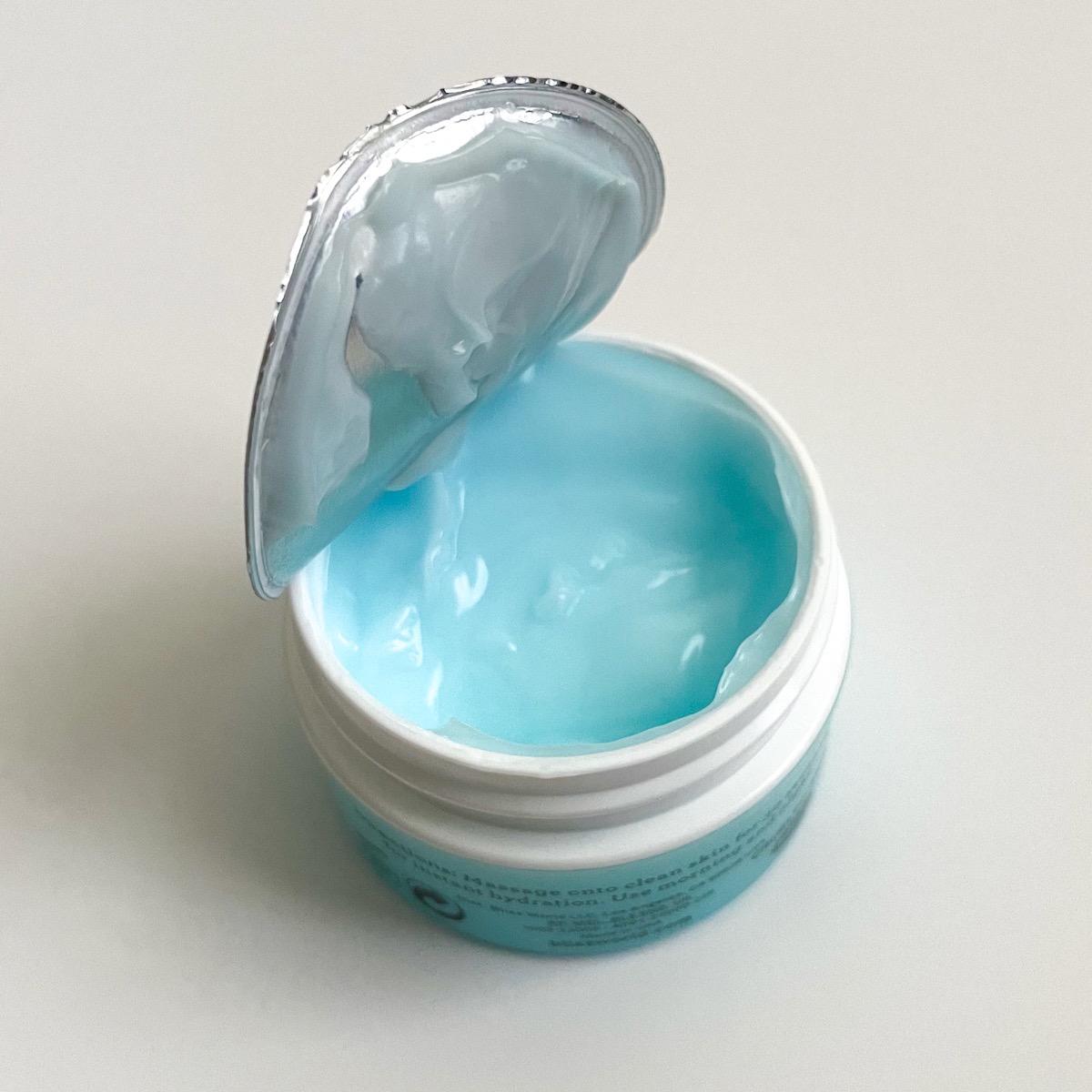 foil seal lifted partially off of jar showing blue moisturizer