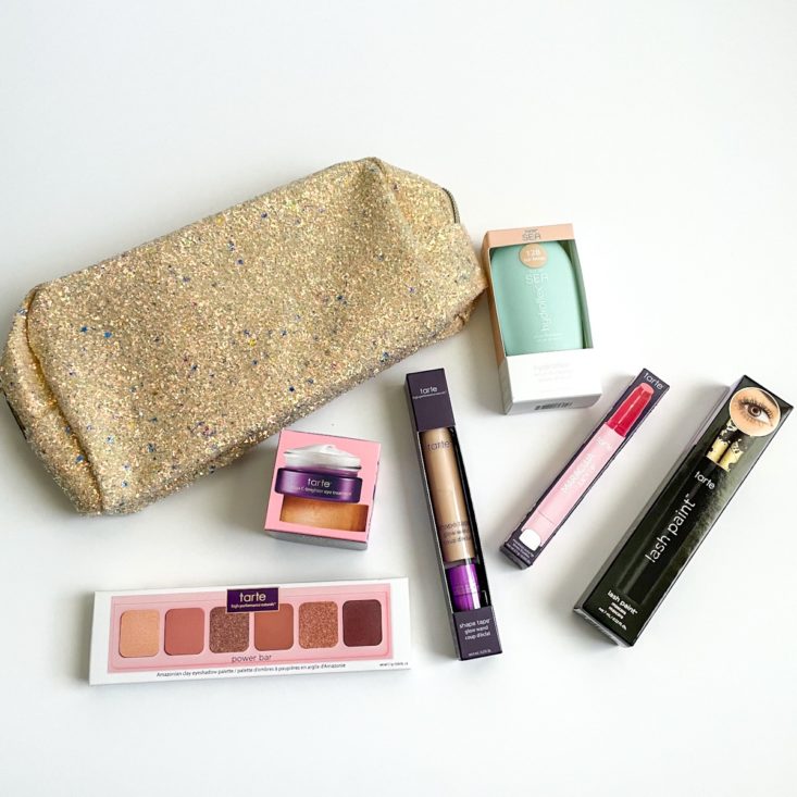 group shot of makeup laying next to sparkly makeup bag