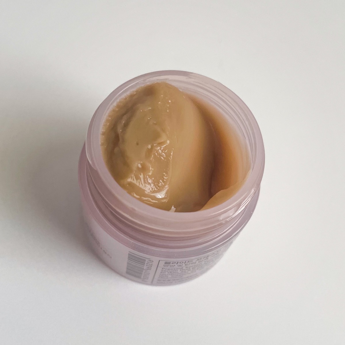 opened pink jar showing thick brown texture of pressed serum