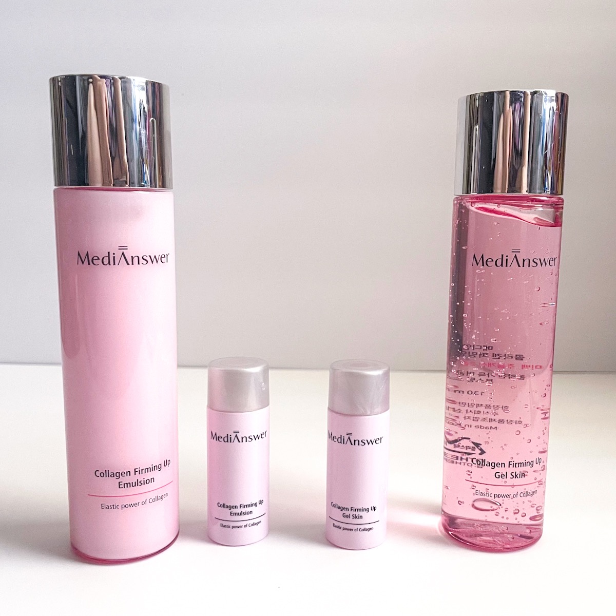 two large pink bottles, one clear and one mild, next to two mini milky pink bottles