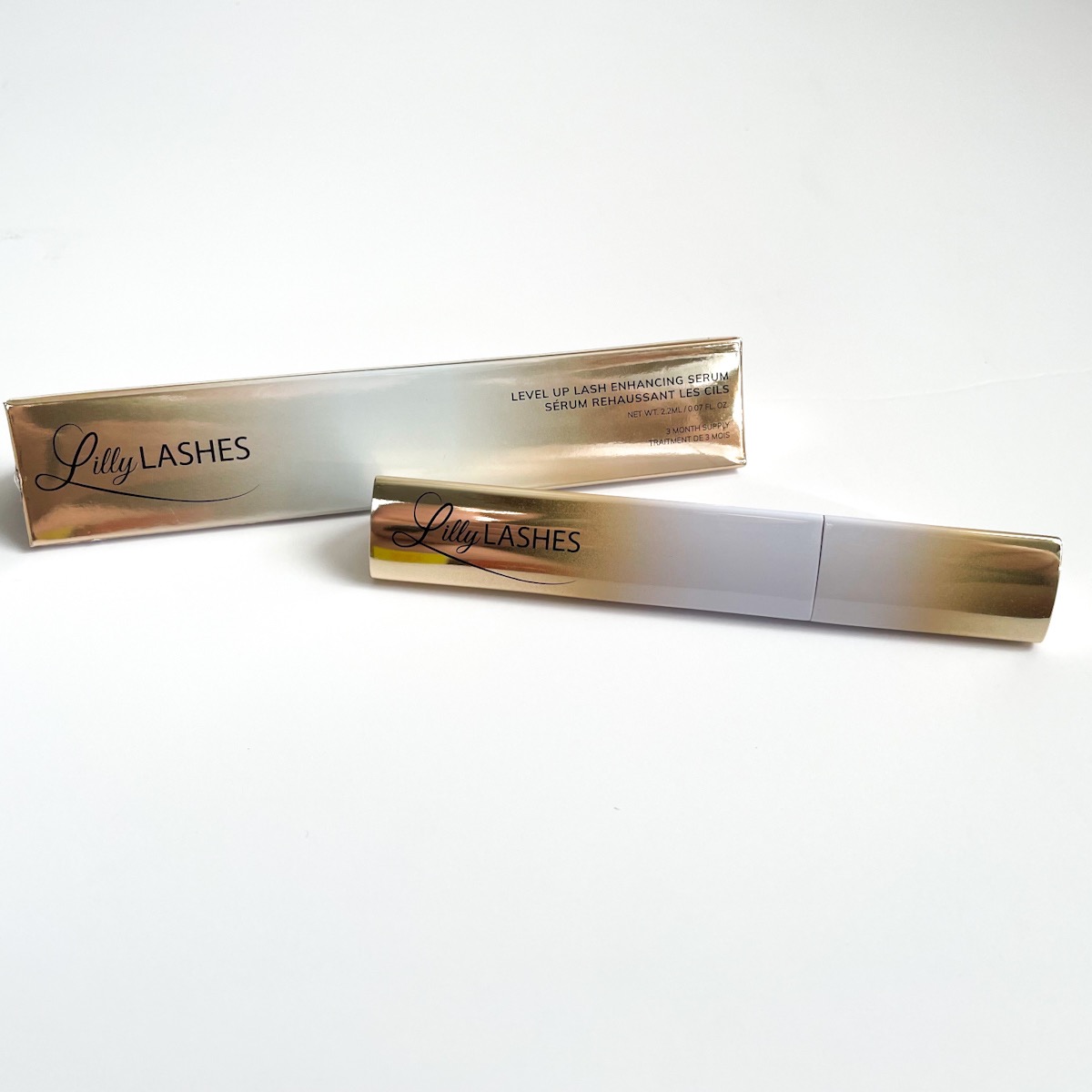 gold and white ombre tube of lash serum next to ombre box