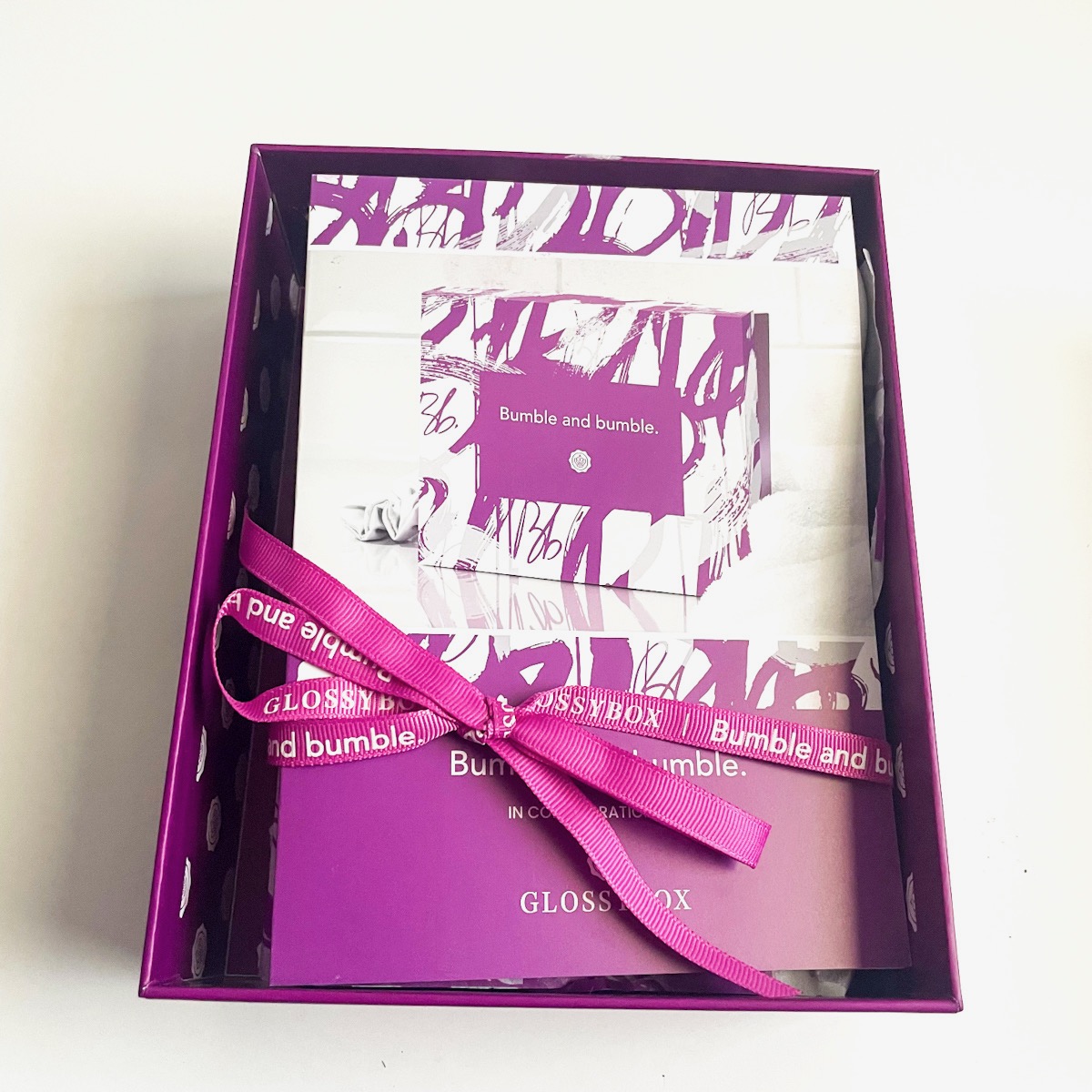 purple and white info sheet laying on top of box contents wrapped in purple ribbon