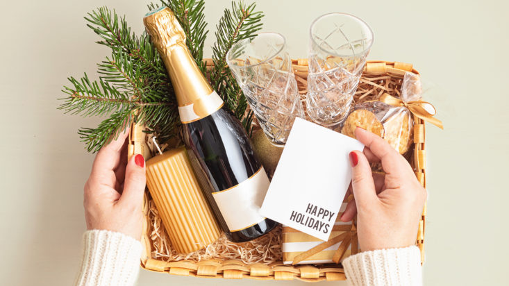 Refined Christmas gift basket for romantic holidays with bottle of champagne, wine glasses, cookies and candle. Corporate or personal present for family and friends.