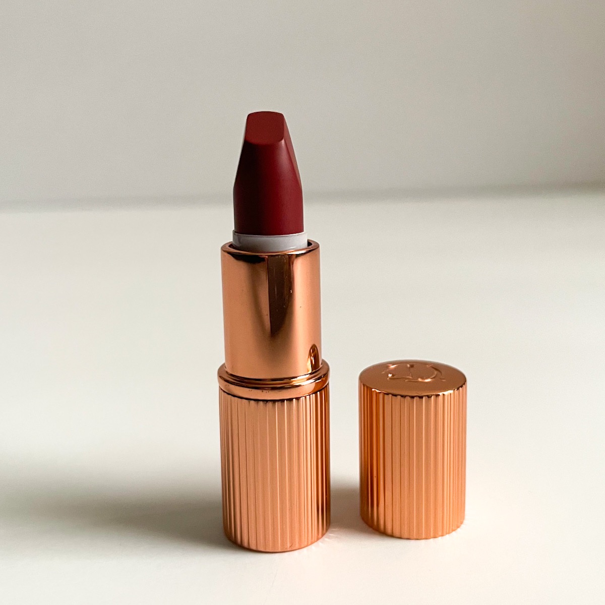 opened mini gold lipstick tube, opened, showing maroon lipstick