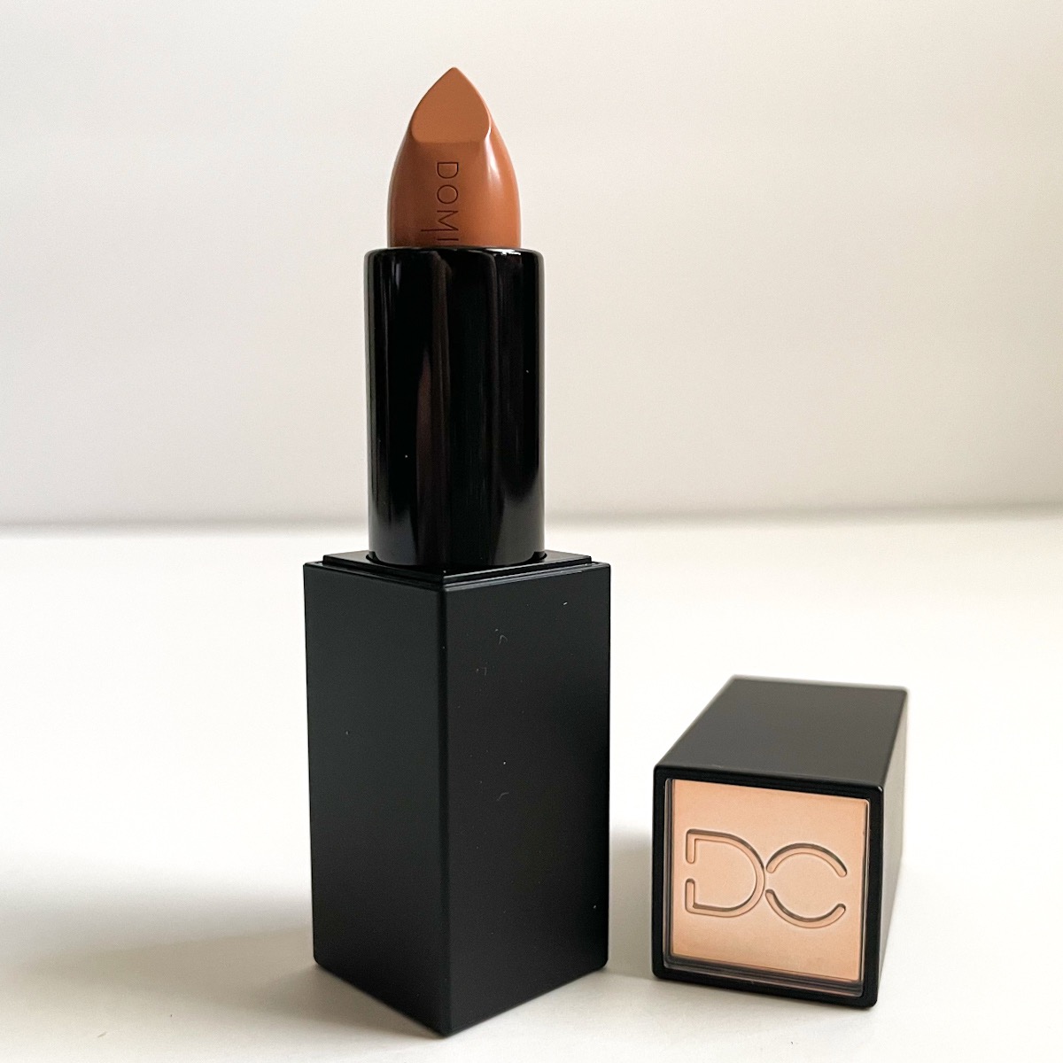 opened black tube of lipstick showing nude lipstick color