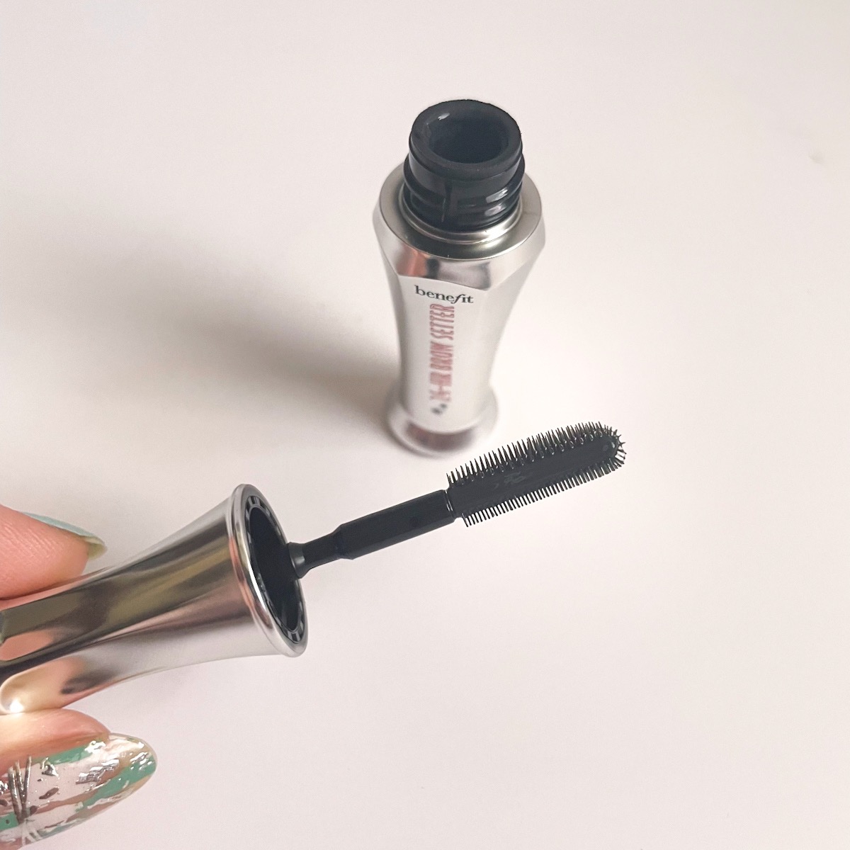 shiny silver tube, opened, showing wand of brow gel brush