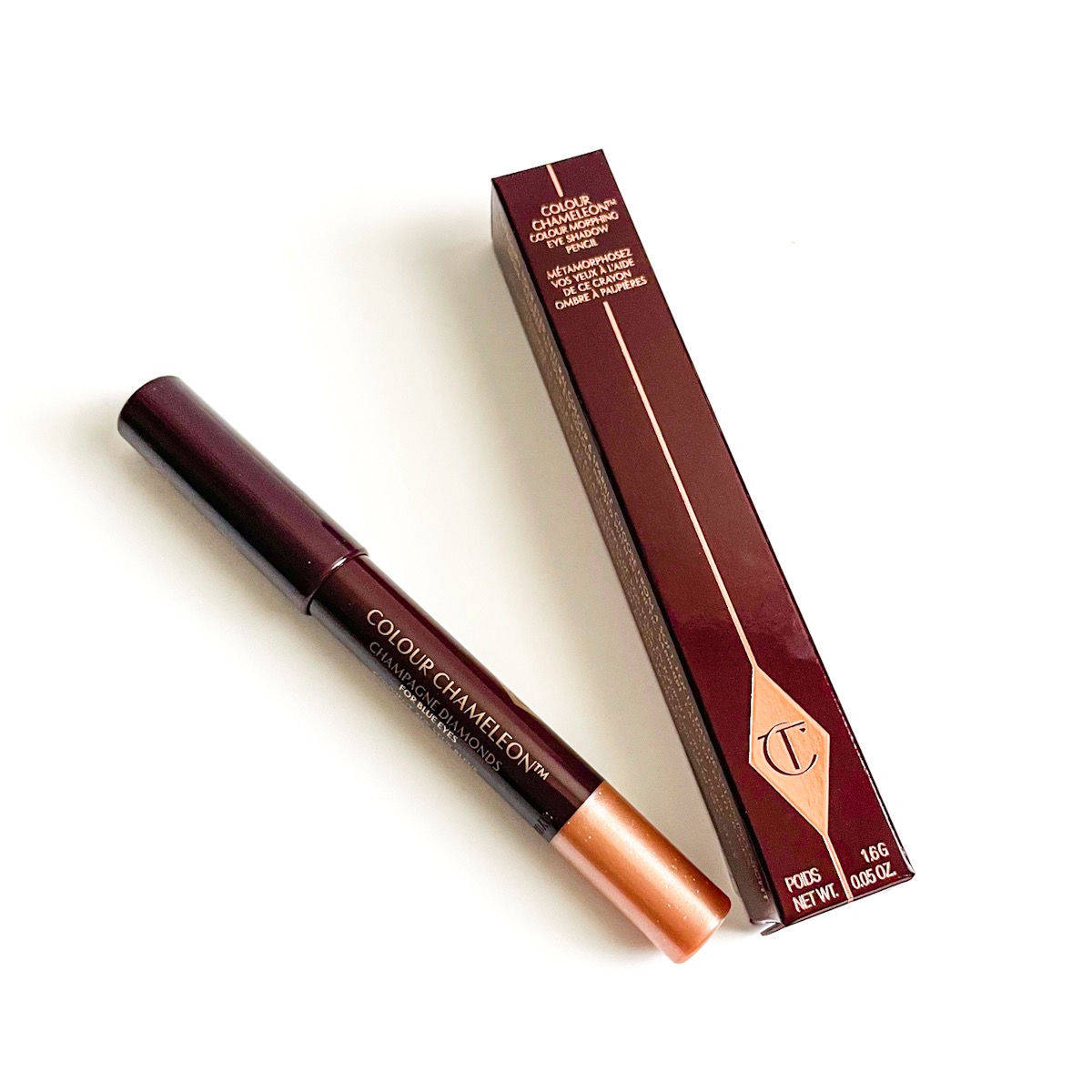 maroon and gold box next to maroon and gold eyeshadow pencil, closed
