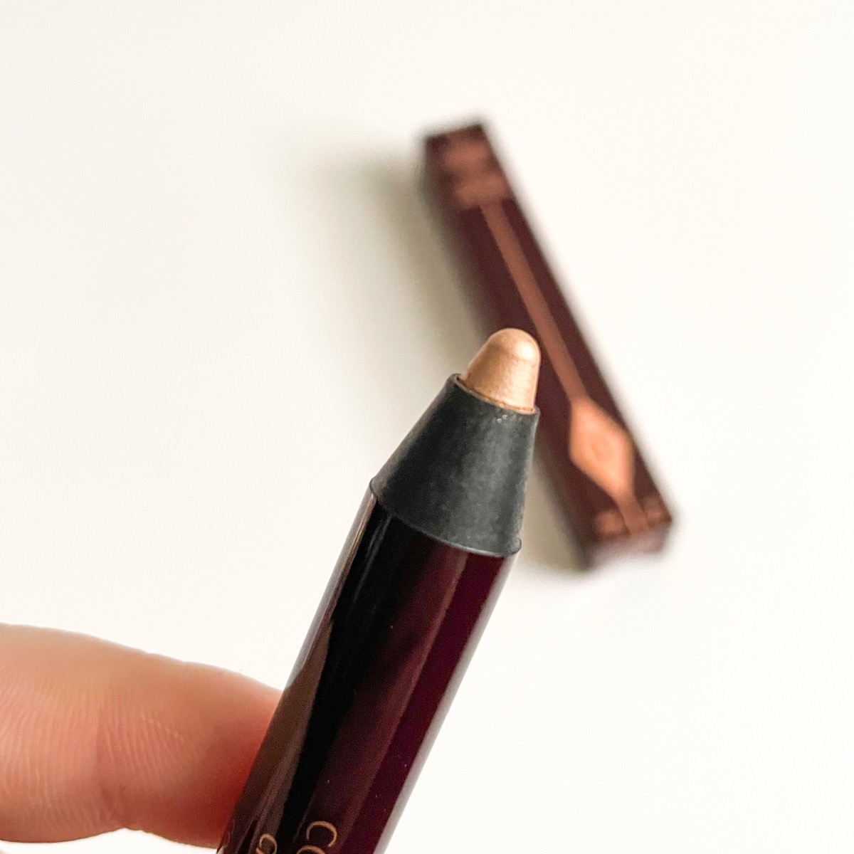 maroon shadow stick, lid off, showing shimmery champagne eyeshadow color