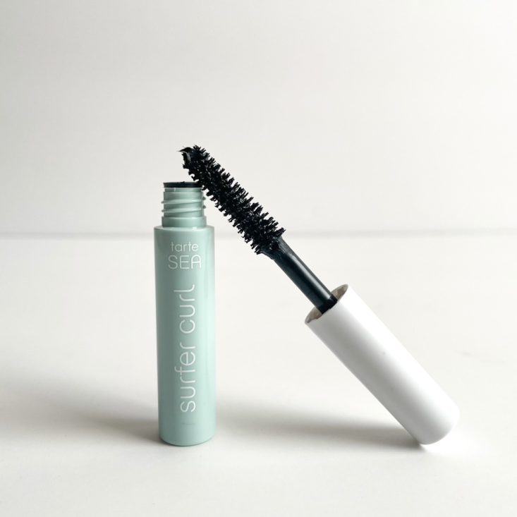 pale blue tube of mascara, opened, with mascara wand leaning against it 