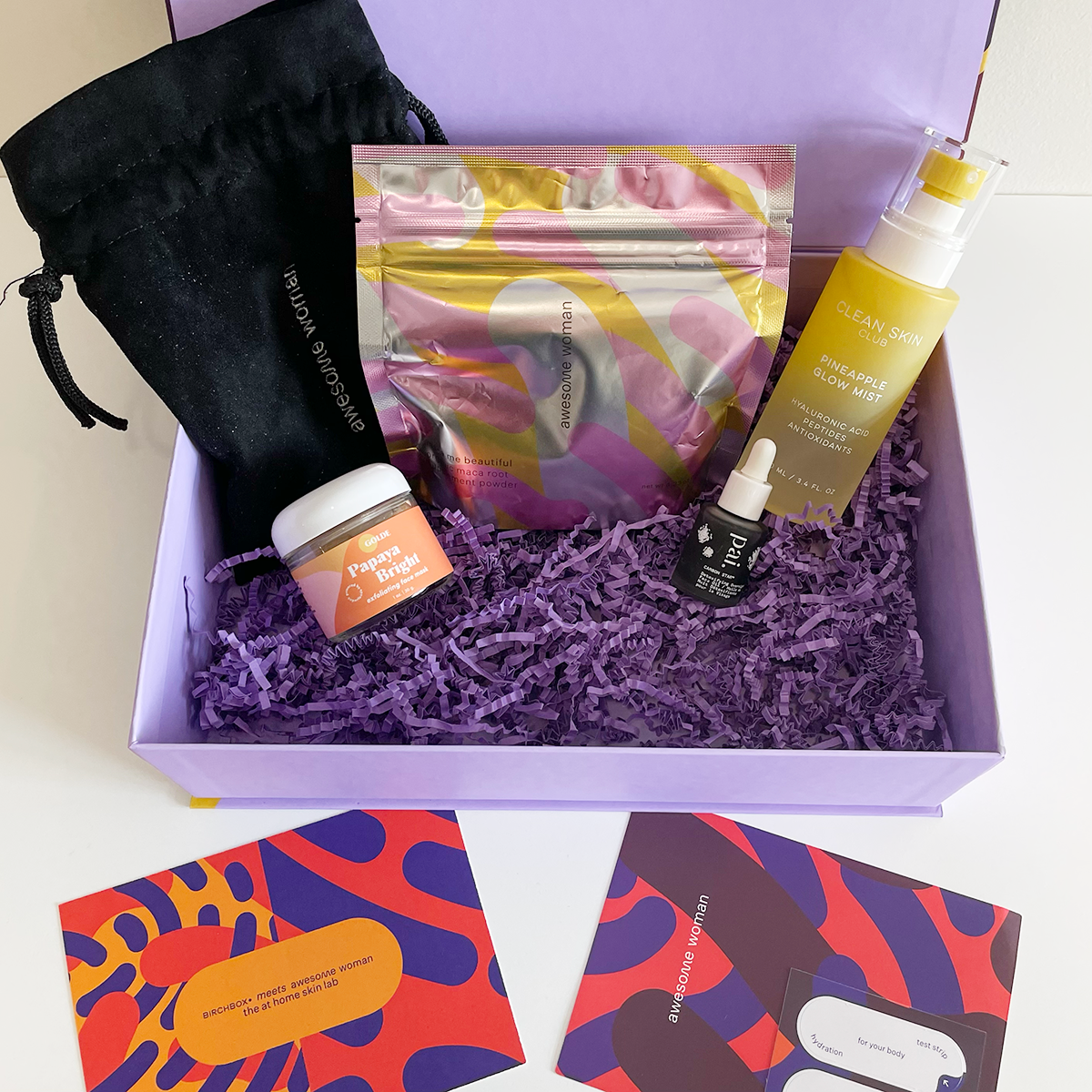 4 beauty products resting inside a lilac box with accompanying info cards