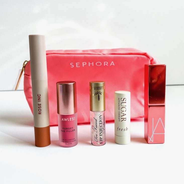 five lip products standing in front of pink makeup bag