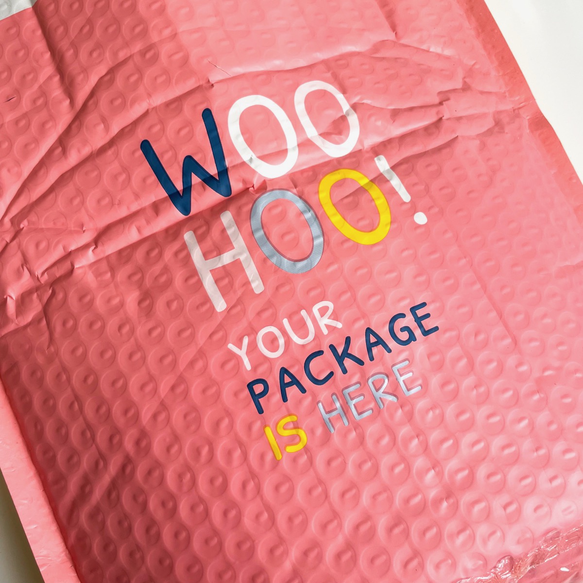 pink bubble mailer that reads "woo hoo your package is here"