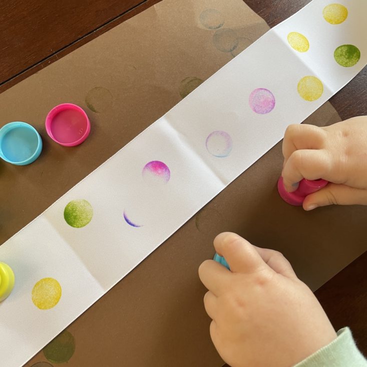 Kid making dot art on a ribbon