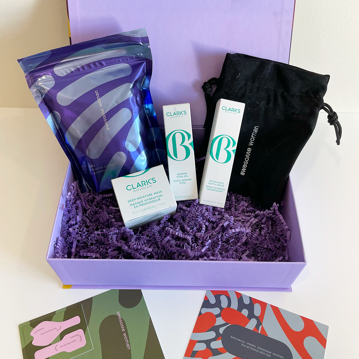 4 beauty products resting inside a lilac box with accompanying info cards