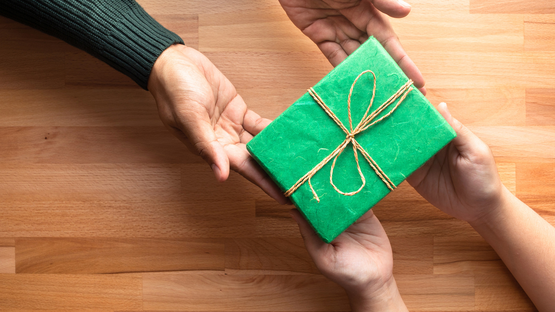 Male gives a gift present to female with wooden copy space background.happiness moment