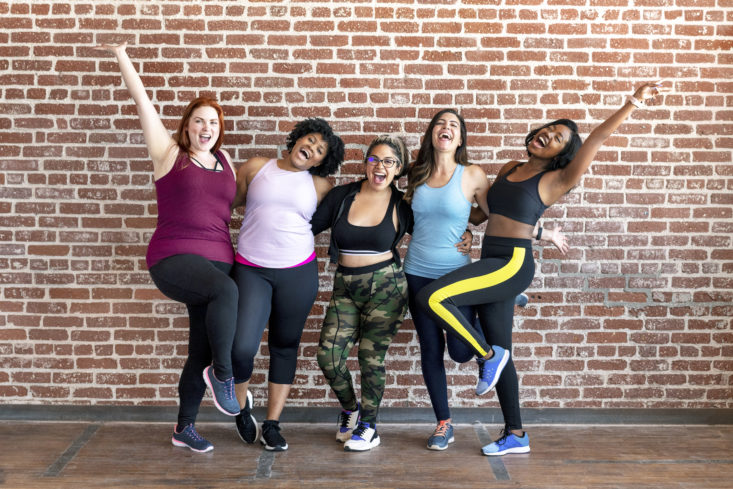 Group of sportive women standing by a brick wall