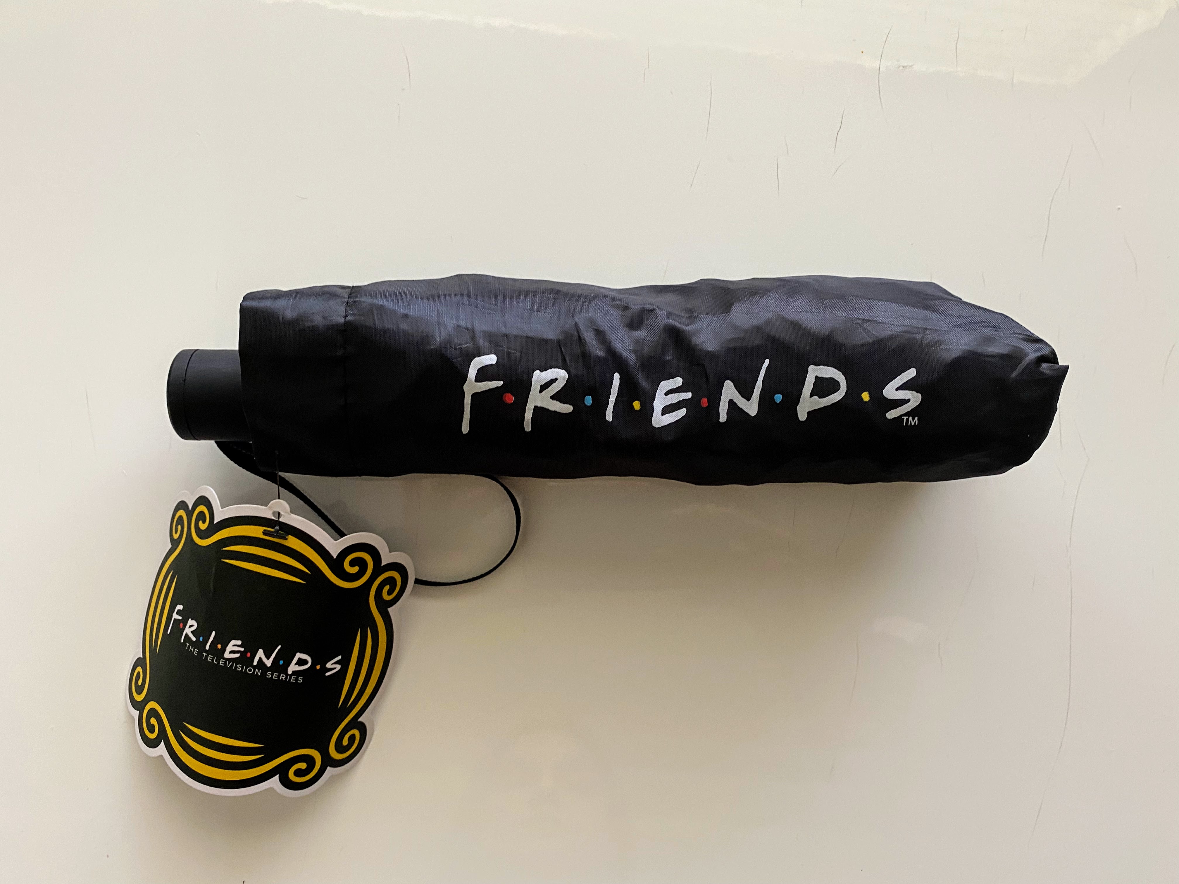 black umbrella wrap with the friends logo