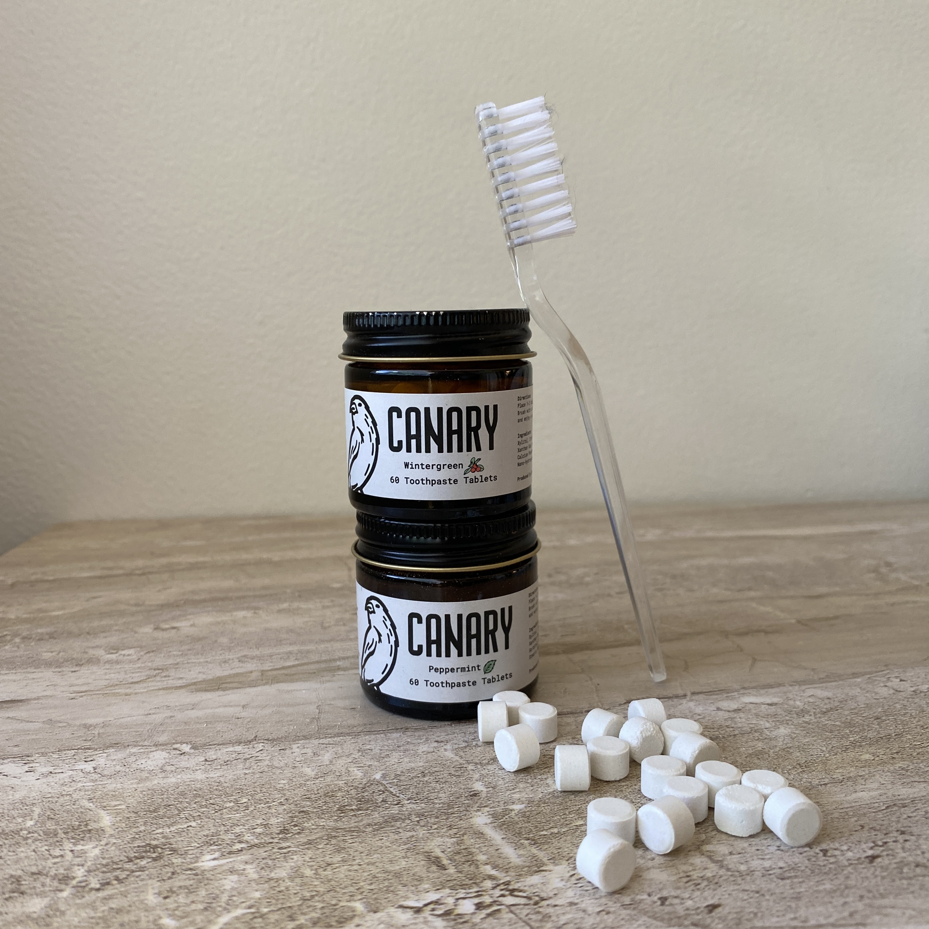 two toothpaste tablets bottles with a toothbrush and tablets