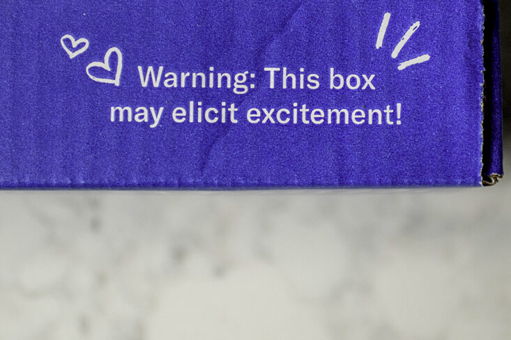 The words warning: this box may elict excitement are seen on a blue book of the month club subscription box