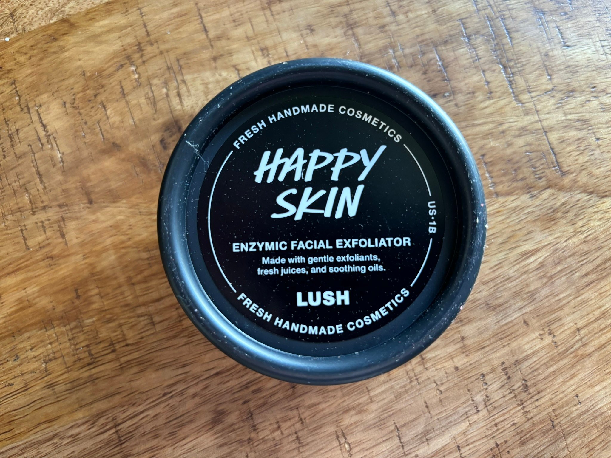 black tub of exfoliator product with white text that reads Happy Skin