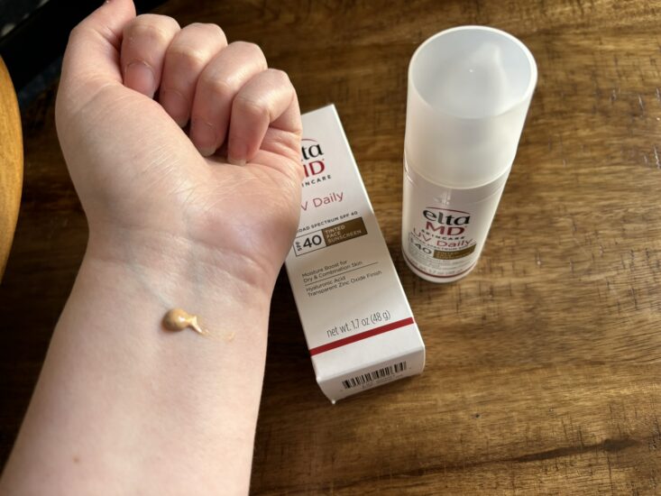 tinted sunscreen applied to arm next to Elta MD sunscreen bottle