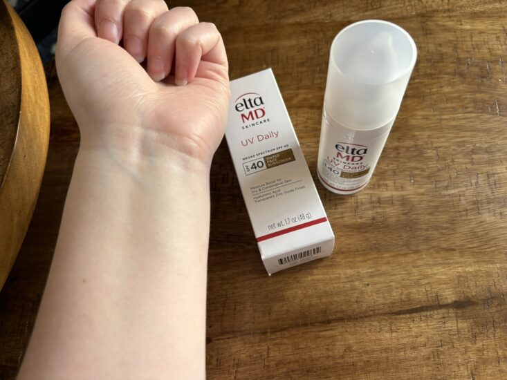 tinted sunscreen applied to arm next to Elta MD sunscreen bottle