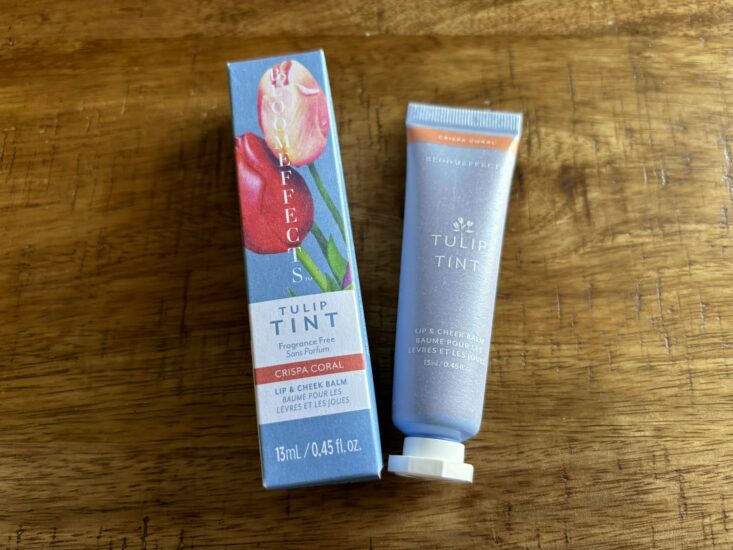 coral-tinted lip and cheek balm in blue tube next to product box