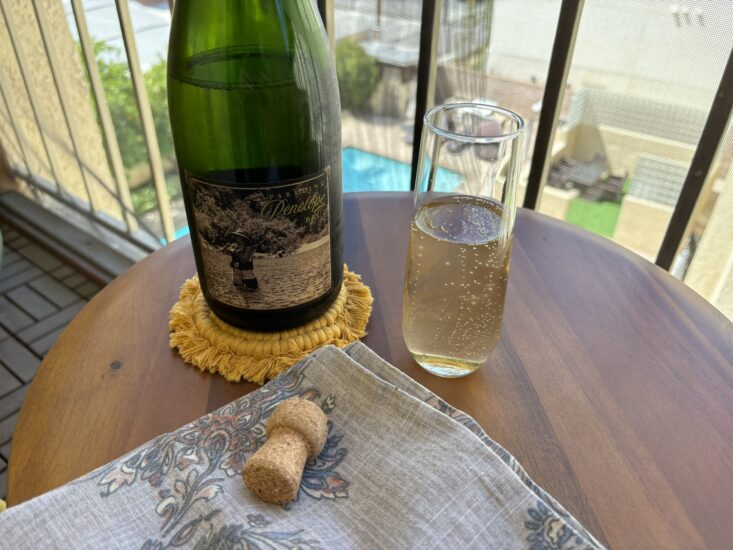 glass of bubbly white wine next to bottle of Sparkling Pénélope California Brut NV 2021