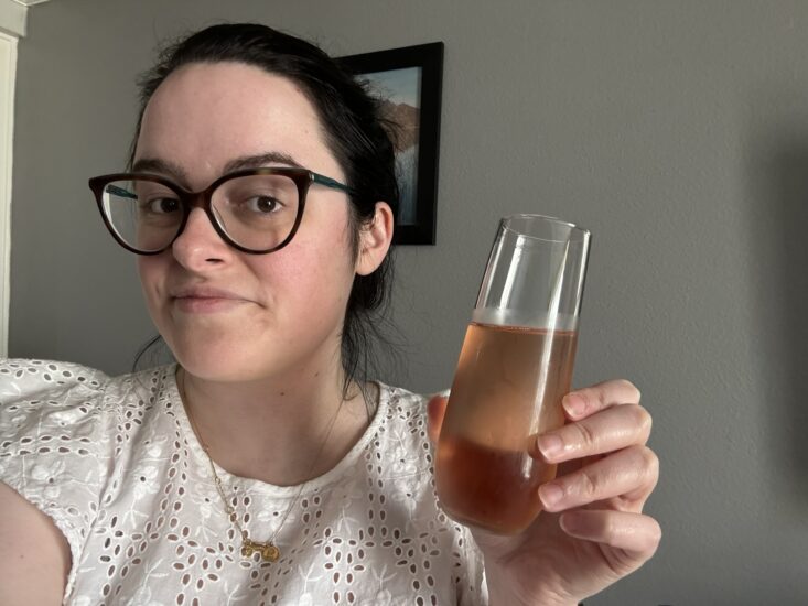 woman holding up a glass of sparkling rose wine